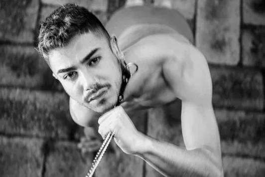 Schwarz-Weiß Fine Art Carpet Print von COMPELLED - DAMIAN von Arjan Spannenburg, mit einem Mann mit Kragen und Kette.