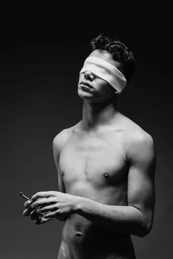 Un retrato conceptual en blanco y negro de un hombre con los ojos vendados sosteniendo una llave.