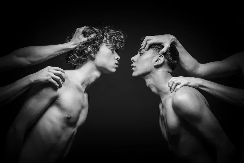 Restraint II af Arjan Spannenburg, et sort-hvidt fotografi af to mænd, der læner sig ind mod hinanden, mens de holdes tilbage af hænder.