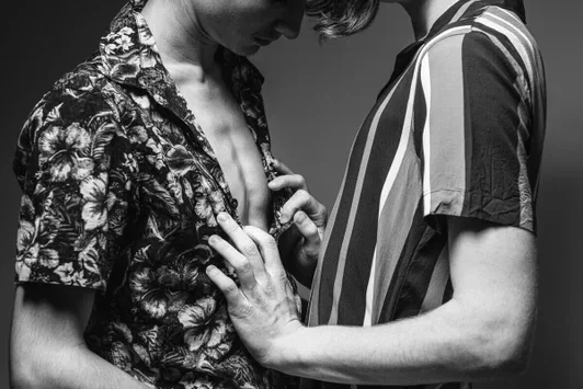 Fotografia concettuale di fine art di Arjan Spannenburg intitolata Tendency, che mostra il momento tattile di una camicia che viene sbottonata come metafora dell'intimità.